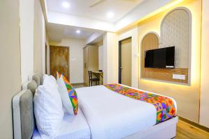 a bedroom with a white bed with a flat screen tv at FabHotel Melody NX in Thane