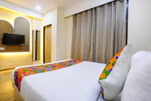 a bedroom with a large white bed with colorful pillows at FabHotel Melody NX in Thane