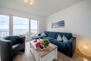 a living room with a blue couch and a chair at Maisonette Fewo Kapteins Lounge by Seeblick Ferien ORO, Rundum Wasser, 6Pers, Sauna, Kamin in Olpenitz