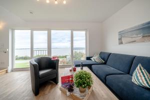 a living room with a blue couch and a chair at Maisonette Fewo Kapteins Lounge by Seeblick Ferien ORO, Rundum Wasser, 6Pers, Sauna, Kamin in Olpenitz