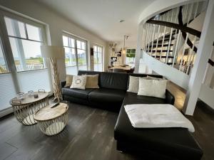a living room with a black couch and a table at Traumferienhaus Sliminde by Seeblick Ferien ORO, direkte Wasserlage E-Säule 6 Pers in Olpenitz