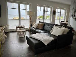 a black leather couch in a living room with windows at Traumferienhaus Sliminde by Seeblick Ferien ORO, direkte Wasserlage E-Säule 6 Pers in Olpenitz