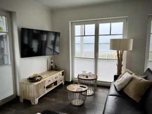 a living room with a couch and a flat screen tv at Traumferienhaus Sliminde by Seeblick Ferien ORO, direkte Wasserlage E-Säule 6 Pers in Olpenitz +30 photos