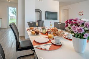 a table with breakfast foods and flowers on it at Schleivilla Lootsen Hus by Seeblick Ferien ORO, 3Etagen,8Pers,Sauna,Kamin in Olpenitz