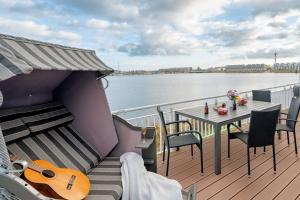 a balcony with a table and a guitar on a boat at Schleivilla Lootsen Hus by Seeblick Ferien ORO, 3Etagen,8Pers,Sauna,Kamin in Olpenitz