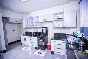 una cucina con mobili bianchi e un piano di lavoro nero di Most Executive house in Naka Lakeview & central a Nakuru