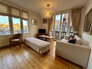 a living room with a couch and a bed and windows at Hyper Centre DEAUVILLE 3 chambres in Deauville