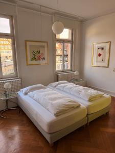 a large bed in a bedroom with two windows at MAVO Hospitality Esslingen Bahnhofstraße in Esslingen