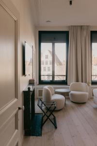a living room with two chairs and a table and two windows at Isidore in Bruges