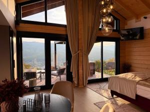 a bedroom with large windows and a bed and a table at Bükk Hill Garden in Miskolc +7 photos