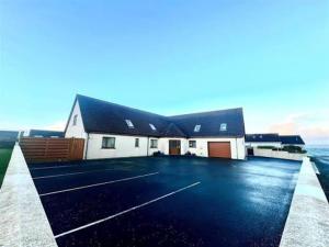 a building with a parking lot next to the ocean at Avalon Guest House in Orkney