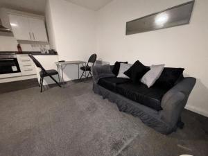 een woonkamer met een zwarte bank en een tafel bij Cosy Modern Studio Apartement in Ilkeston