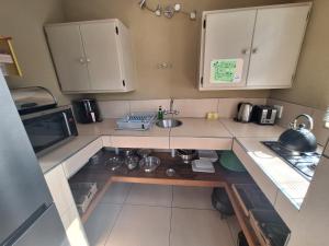 a small kitchen with a sink and a microwave at Jackalberry Ridge by Dream Resorts in Marloth Park