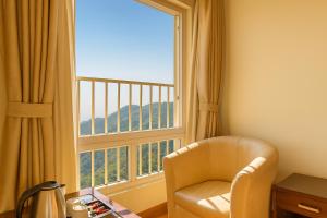 a room with a chair and a large window at Hotel Samrat - On Mall Road in Mussoorie