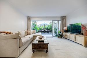 Una sala de estar con un sofá y un televisor. en La Palma Sunshines Heart beside The Village, en Sunshine Beach