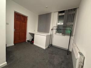 een lege kamer met een koelkast en een deur bij Cosy Modern Studio Apartement in Ilkeston