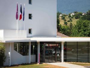 a building with two flags in front of it at Mercure Aix-les-Bains Domaine de Marlioz Hôtel & Spa in Aix-les-Bains