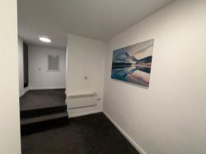 een hal met witte muren en een schilderij aan de muur bij Cosy Modern Studio Apartement in Ilkeston