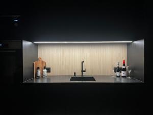 a kitchen counter with a sink and bottles of wine at Fjordview Arctic Lodge with sauna and Jacuzzi in Lyngværet