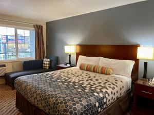 a hotel room with a bed and a chair at Travelers Inn Eugene University in Eugene +13 photos