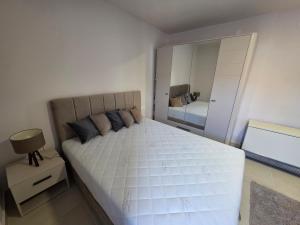 Un dormitorio con una gran cama blanca y un espejo. en Apartman Bibi centar, en Niš