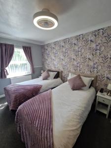 ペイントンにあるAmbassador Guest Houseのホテルルーム内のベッド2台 花柄の壁紙
