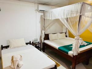 a bedroom with two beds and a canopy bed at Palitha Homestay in Sigiriya