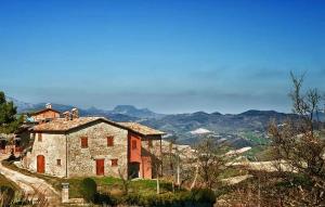 an old house on a hill with mountains in the background at 2 Bedroom Nice Apartment In Sant'angelo In Vado in Piandimeleto