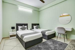 two beds in a room with a mirror and a chair at Hotel Sukoon & Banquet Hall Near Bhopal Railway Station in Bhopal