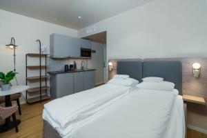 a bedroom with a large white bed and a kitchen at MAYA Apartments - Frogner in Oslo