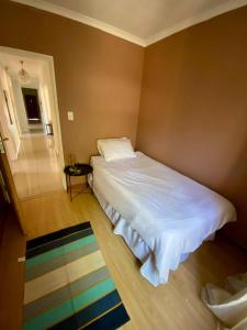 a bedroom with a large white bed and a rug at Ubuntu Guest House in Cape Town