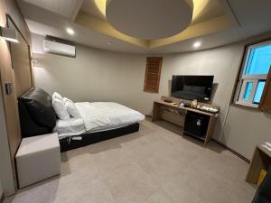 a bedroom with a bed and a tv and a chair at 계룡 호텔 스테이318 in Gyeryong
