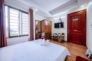 a bedroom with a white bed with a white cat on it at Thu Ha Hotel in Uông Bí