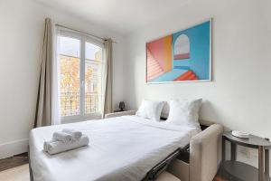 a bedroom with a white bed and a window at Cosy Studio Asnieres in Les Grésillons