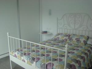 カラ・ボナにあるFerienhaus Casa Aina Mit Pool Und Sonnenterrasseの白いベッド1台、カラフルな掛け布団が備わるベッドルーム1室が備わります。