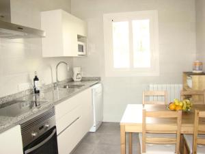 カラ・ボナにあるFerienhaus Casa Aina Mit Pool Und Sonnenterrasseのキッチン(白いキャビネット、フルーツボウル付きのテーブル付)