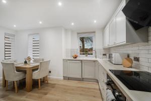 een keuken met witte kasten en een tafel en stoelen bij Milton Keynes 3BR,Relaxing Home, Sleeps 5, Families Stays, Free Parking in Milton Keynes