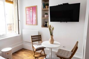 een woonkamer met een tafel en stoelen en een televisie bij DA-3-TURENNE-BM near Place des Vosges in Parijs