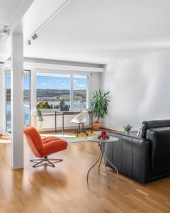 a living room with a couch and a table and a chair at EXQUIS Design 3-Room Apartment KNOLL I Zurich Lake View I Balcony I Family-Friendly in Männedorf