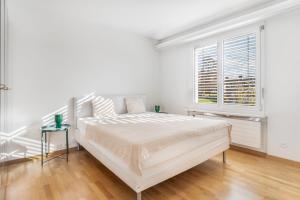 a white bedroom with a bed and a window at EXQUIS Design 3-Room Apartment KNOLL I Zurich Lake View I Balcony I Family-Friendly in Männedorf