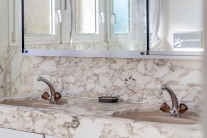 a bathroom with two sinks and two mirrors at EXQUIS Design 3-Room Apartment KNOLL I Zurich Lake View I Balcony I Family-Friendly in Männedorf