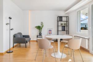 a white living room with a table and chairs at EXQUIS Design 3-Room Apartment KNOLL I Zurich Lake View I Balcony I Family-Friendly in Männedorf +11 photos