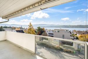 a balcony with a view of the water at EXQUIS Design 3-Room Apartment KNOLL I Zurich Lake View I Balcony I Family-Friendly in Männedorf