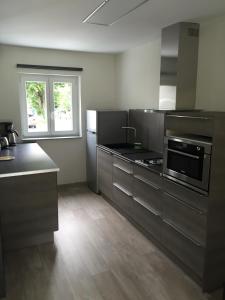 a large kitchen with stainless steel appliances and a window at Le Clos du Silberthal in Steinbach