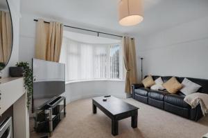 a living room with a black couch and a table at Pass the Keys Seaside Sanctuary Cullercoats – Walk to the Beach in Cullercoats