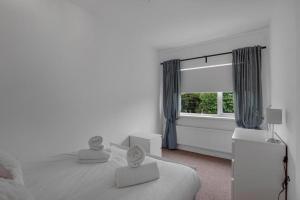 a white bedroom with a bed and a window at Pass the Keys Seaside Sanctuary Cullercoats – Walk to the Beach in Cullercoats
