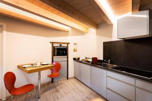 a kitchen with red chairs and a table in it at Bomaloft - Quiet by the River, Walk to Everything in Zermatt