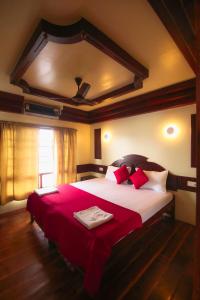 a bedroom with a large bed with a red blanket at JCT Exclusive 3 Bedroom Private Houseboat with All Meals in Alleppey