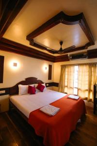 a bedroom with a large bed with red sheets at JCT Exclusive 3 Bedroom Private Houseboat with All Meals in Alleppey