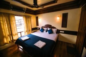a bedroom with a large bed with blue sheets and a window at JCT Exclusive 3 Bedroom Private Houseboat with All Meals in Alleppey +5 photos